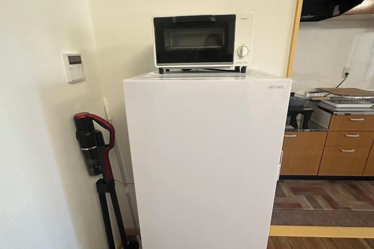Una cocina compacta con un refrigerador blanco, un microondas encima y un lavamanos pequeño.