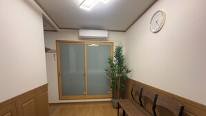 A hallway with wooden flooring, a bench, a potted plant, a clock, and a sliding door with frosted glass panels. - KAIYOUTATEISHI (Tokyo)