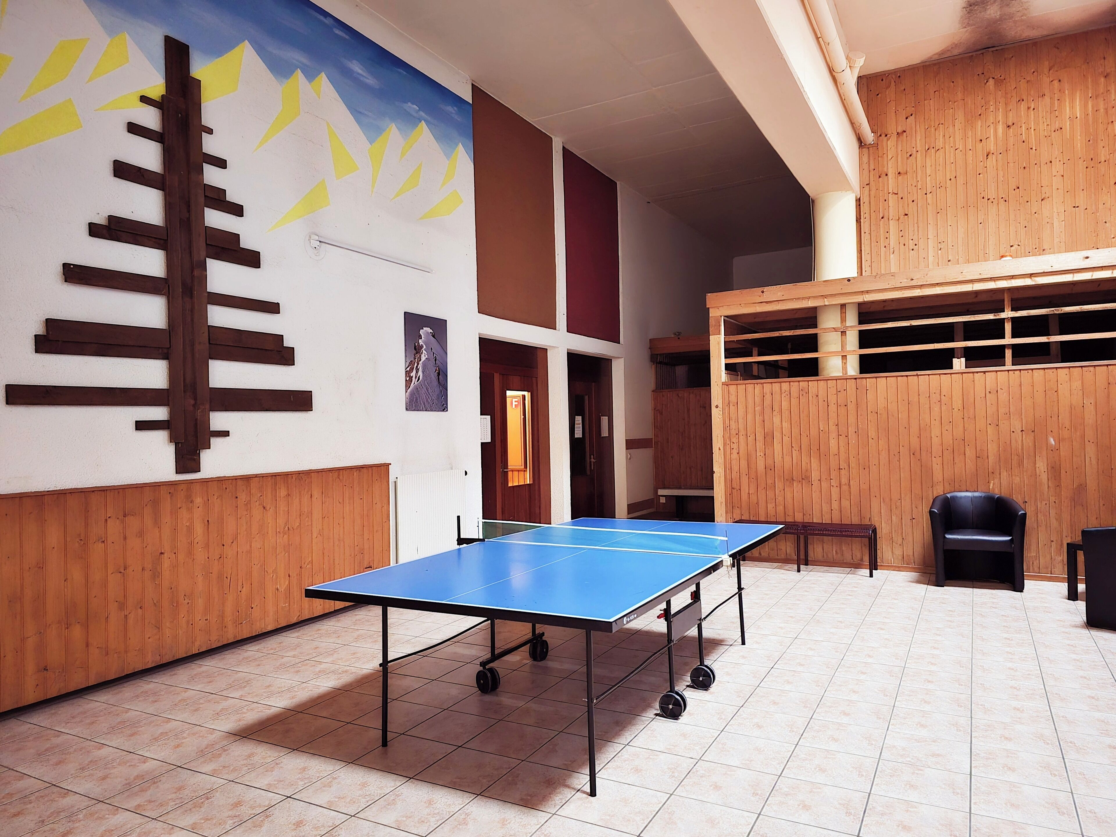 Una mesa de ping pong en una habitación con paredes de madera y un mural.