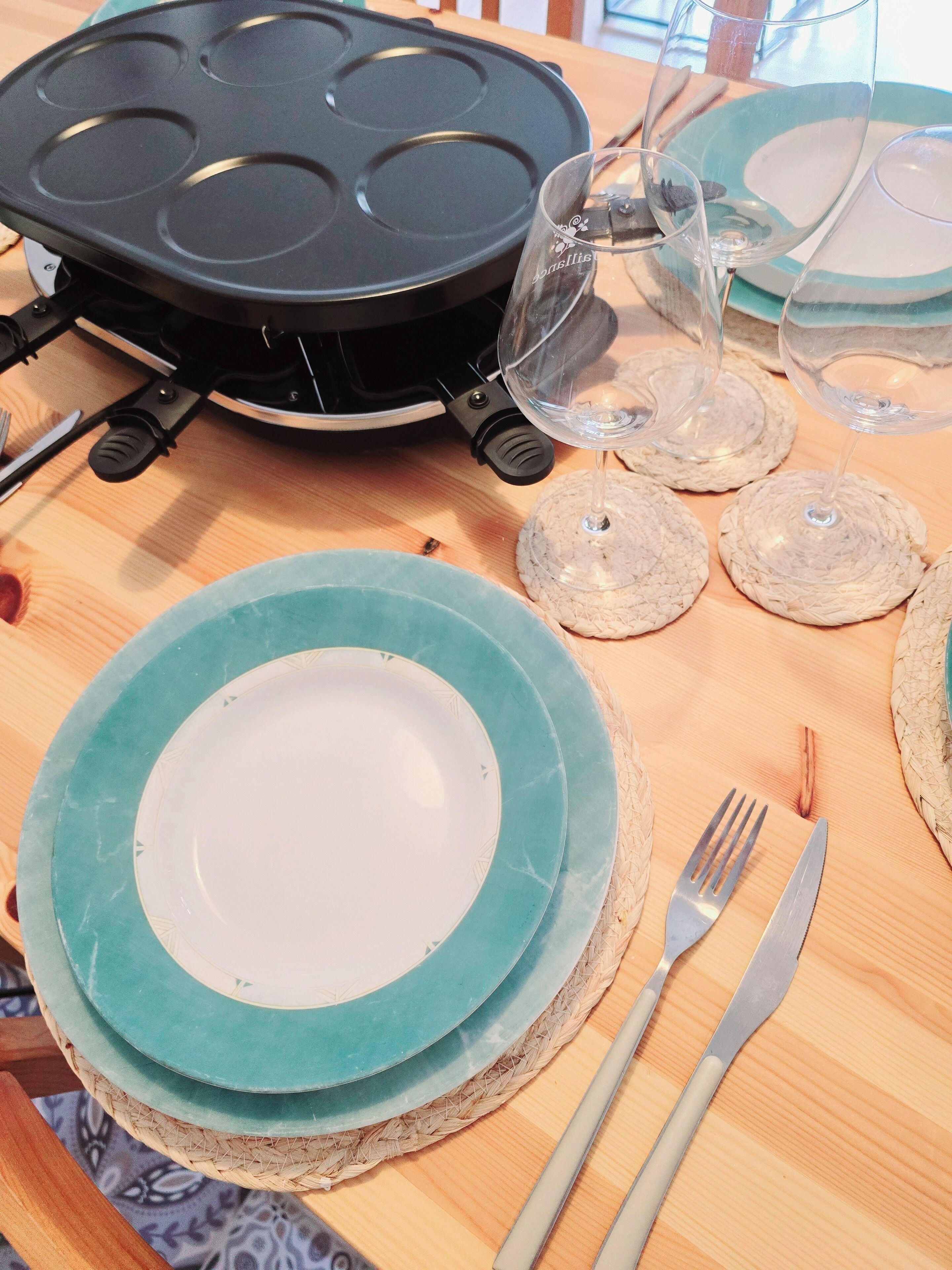 A dining table with plates, cutlery, and a waffle iron.