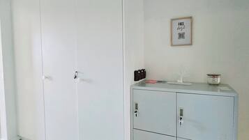 Ein Zimmer mit einem weißen Kleiderschrank, einem Metall-Aktenschrank und einem gerahmten Schild an der Wand.