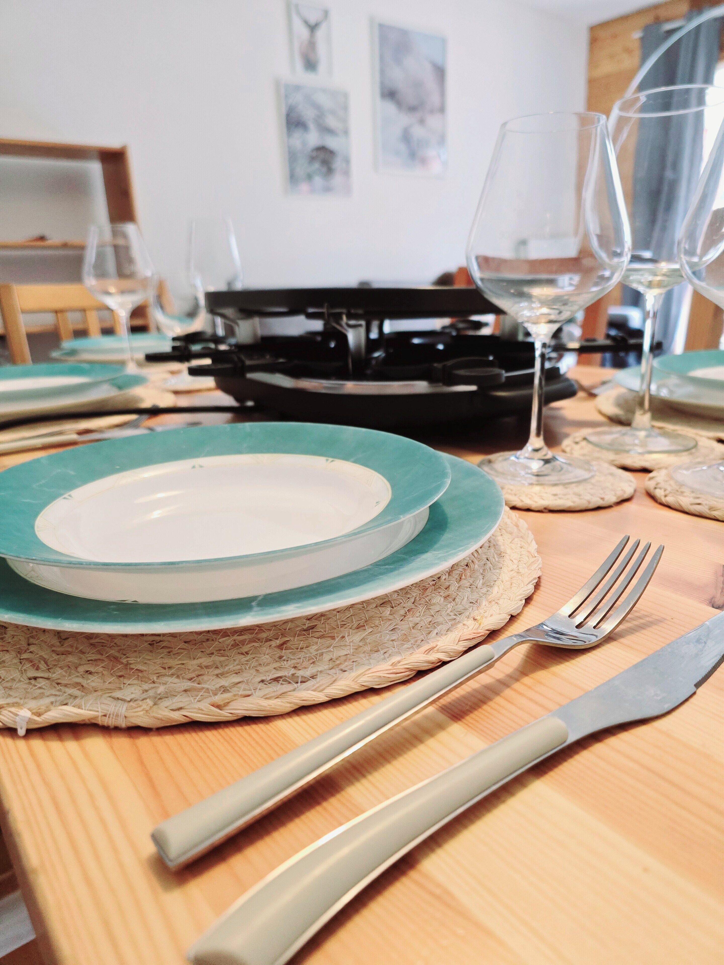 A dining table set with plates, glasses, and cutlery.