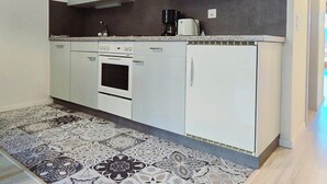 Una cocina moderna con gabinetes blancos, microondas, cafetera y horno.