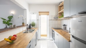 A modern kitchen with a wooden countertop, stainless steel appliances, and a view to the outside. - Family-Friendly Apartment in Carvoeiro (Carvoeiro)