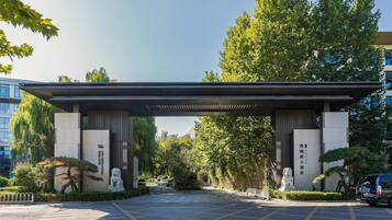 Stunning entrance with a covered walkway, flanked by majestic statues and surrounded by lush greenery.