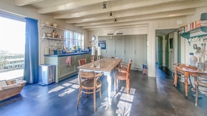 A spacious kitchen with a large island, wooden dining table, and chairs. There is a window providing natural light and a view of the outdoors. - Nice home in Westerland (Westerland)