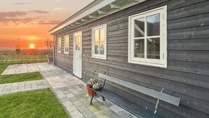 A two-story house with a covered porch, a small garden, and a sunset view. - Nice home in Westerland (Westerland)