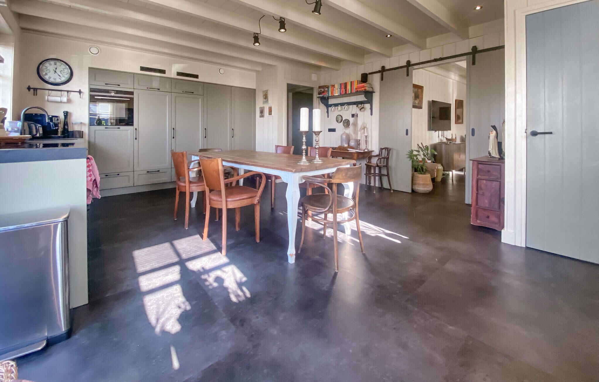 A spacious kitchen with a central island, white cabinetry, and a dining area with wooden chairs.
