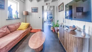 A modern living room with a leather sofa, a wooden coffee table, and a kitchen area with a wooden counter and potted plants. - Nice home in Westerland (Westerland)