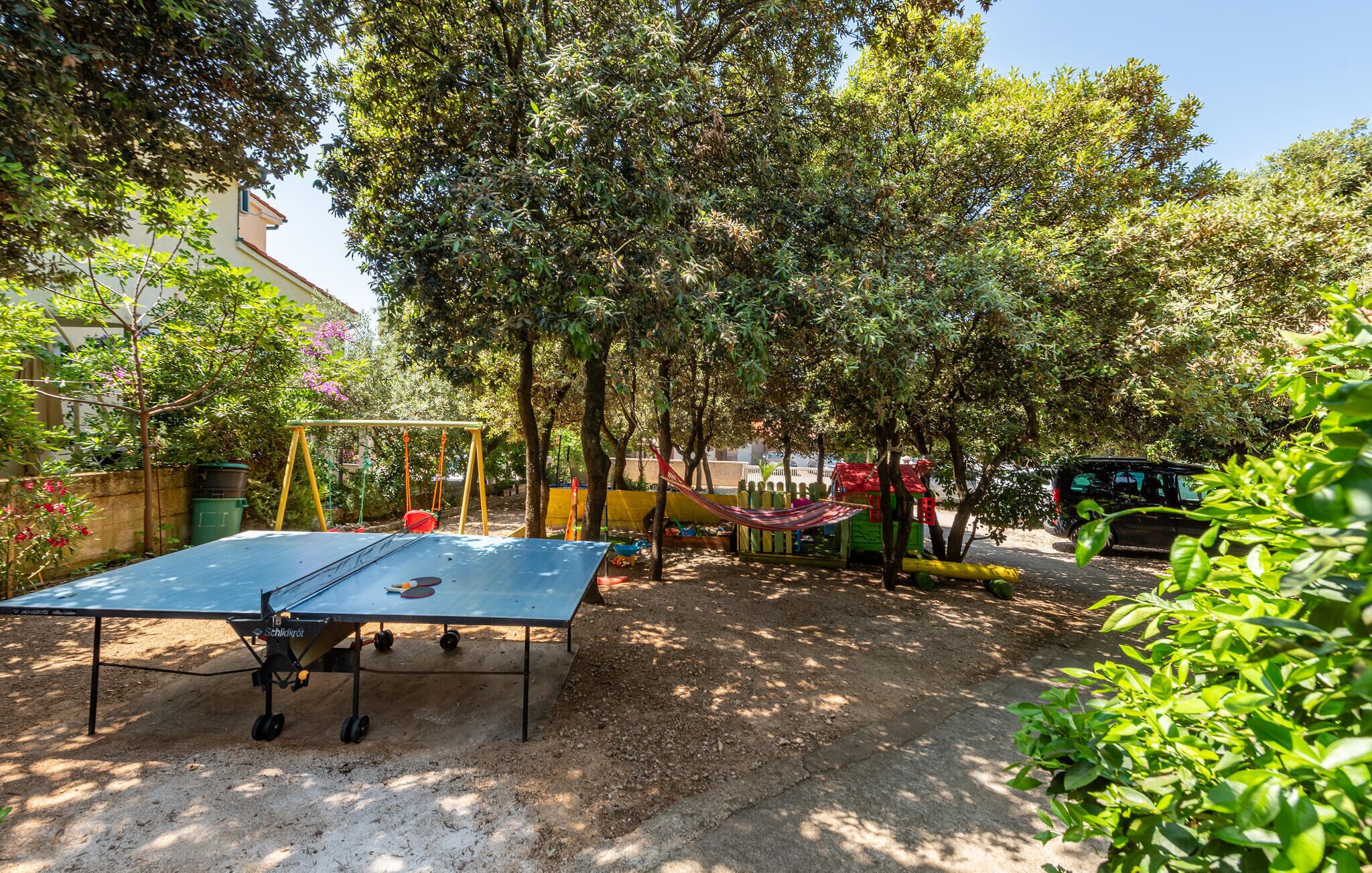 Une aire de jeux équipée d’une table de ping-pong, de balançoires et d’un toboggan.