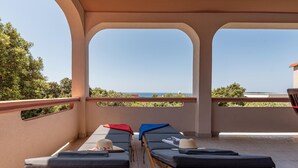 A balcony with two lounge chairs, a wooden table, and a view of the sea. - Amazing apartment in Mandre with WiFi (Mandre)