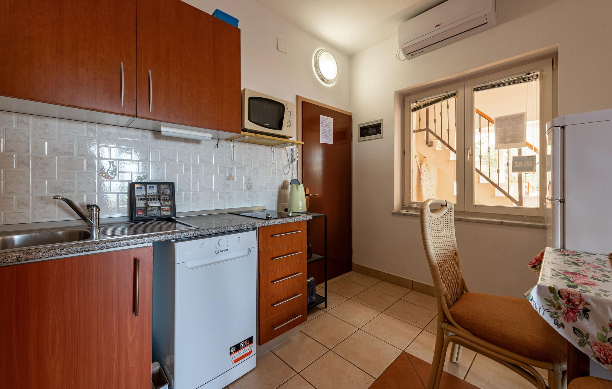 A compact kitchen with wooden cabinets, a built-in microwave, a coffee maker, and a small refrigerator.