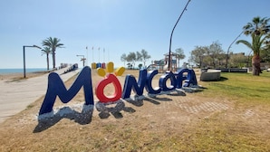 A beachside sign with the name 'MONCORA' in large letters.