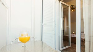 A glass of orange juice on a table in a room with a sliding glass door leading to a bedroom.
