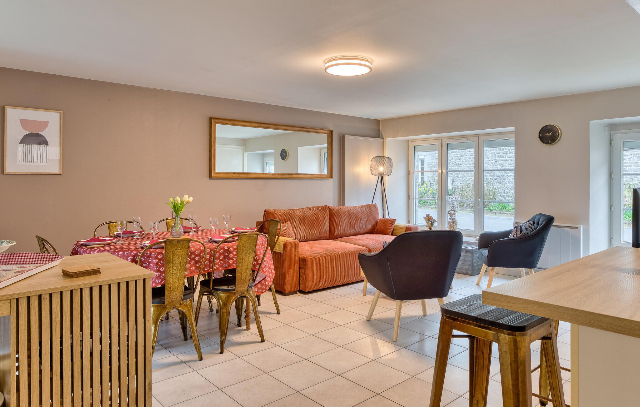 A dining area with a table set for four, a sofa, and a floor lamp.