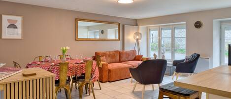 A dining area with a table set for four, a sofa, and a floor lamp.