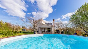 Una casa moderna amb una piscina, un porxo cobert i un terrat de fusta.