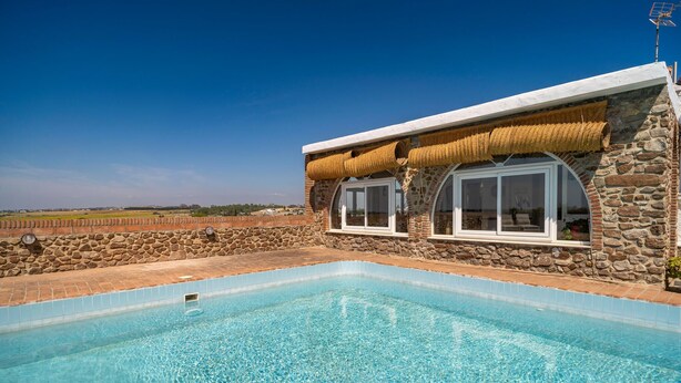 A stone building with a pool, large windows, and a view of the countryside. - Stunning home in Conil de la Frontera (Conil de la Frontera)