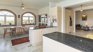 A spacious kitchen with a large island, white cabinetry, and a view through the windows. - Stunning home in Conil de la Frontera (Conil de la Frontera)