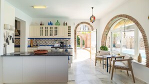 A modern kitchen with a central island, white cabinets, and blue and white patterned backsplash. - Stunning home in Conil de la Frontera (Conil de la Frontera)