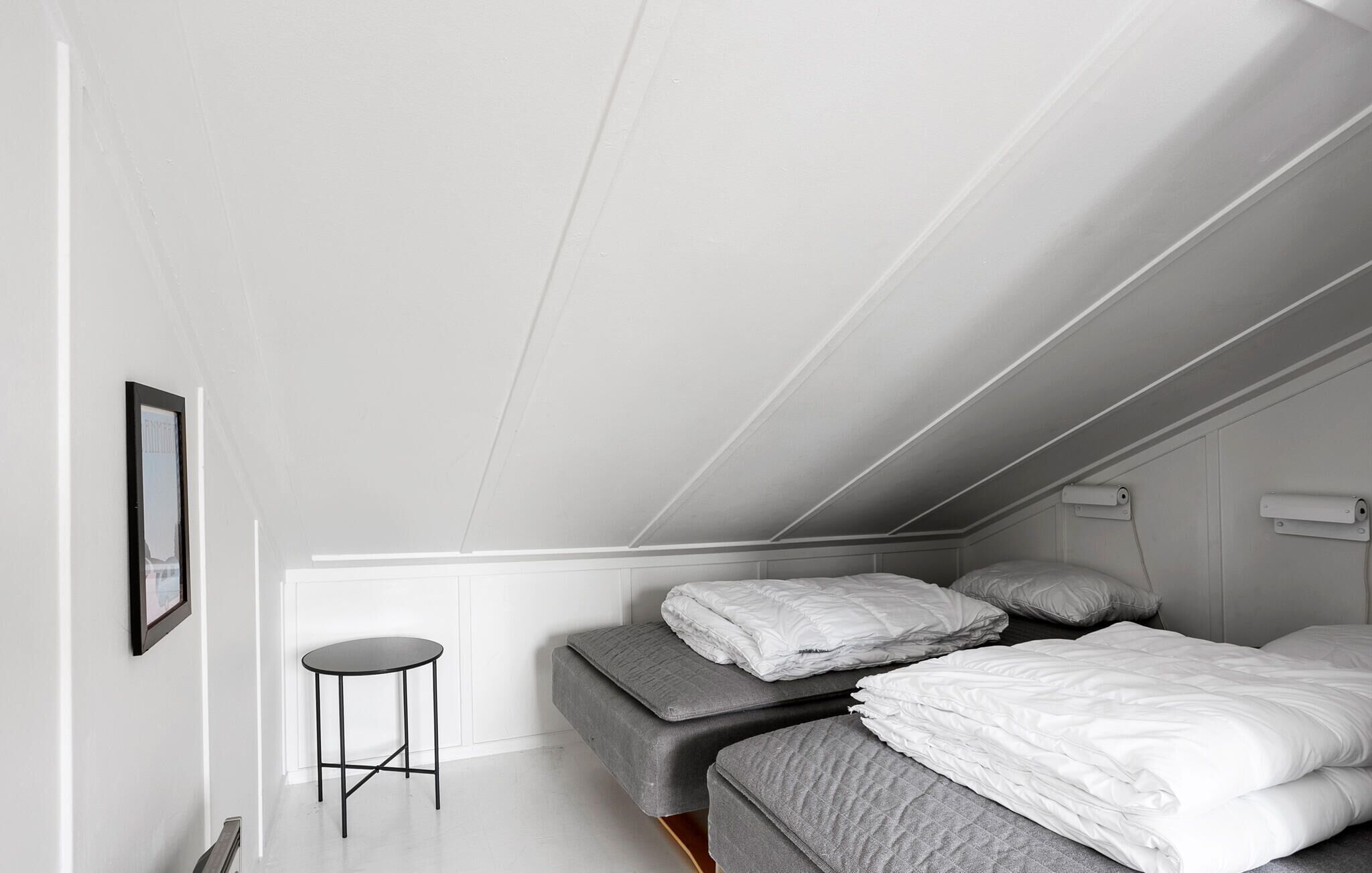 Ein Schlafzimmer mit einem Hochbett, einem kleinen runden Tisch und einem gerahmten Bild an der Wand.