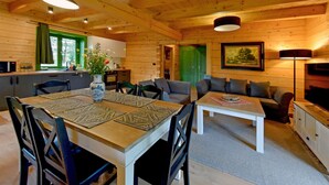 A cozy cabin interior with a dining area, a sofa, and a kitchen. - Cozy home in Czaplinek with lake view (Czaplinek)