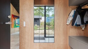 A modern interior with a wooden door leading to a glass door, a clothing rack, and a grey cabinet.