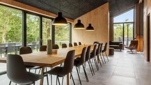 A modern conference room with a long wooden table, black chairs, and pendant lighting.