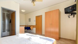 Une chambre d’hôtel comprenant un lit, un bureau avec une chaise, une télévision et une armoire.