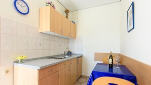 Une cuisine compacte avec des meubles en bois, un  évier et un petit coin repas comprenant une table et des chaises.