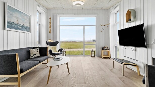 Un salon moderne avec un canapé, une table basse et un téléviseur fixé au mur.