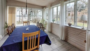 A dining area with a table set for four, wooden chairs, a chandelier, and large windows with curtains. - Amazing home in ör with WiFi (Ör)