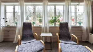 A room with two chairs facing a table, large windows with curtains, and potted plants on the windowsills. - Amazing home in ör with WiFi (Ör)