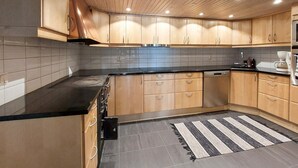 A modern kitchen with wooden cabinets, a black countertop, and a striped rug. - Amazing home in ör with WiFi (Ör)