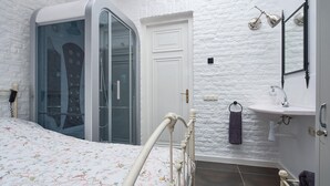 A bedroom with a bed, a walk-in closet, a bathroom with a sink and mirror, and a white brick wall. - Pet friendly home in Ospel with WiFi (Ospel)