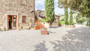 Un edificio de piedra con puerta de madera, una escalera y un camino de entrada de grava.
