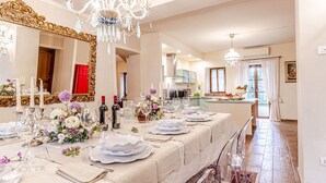 Un comedor espacioso con una larga mesa dispuesta para una comida, elegantes candelabros y un espejo grande.