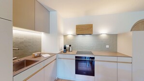 A modern kitchen with a built-in dishwasher, a kettle, and a coffee maker on the counter.