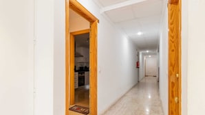 A hallway with wooden doors, a kitchen area visible through one door, and a tiled floor. - Diana Apartment (Teulada)