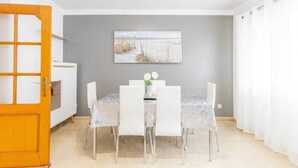 A dining area with a table set for four, a grey wall, and a painting above the table. - Diana Apartment (Teulada)