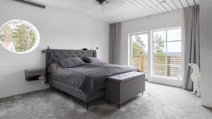 Een moderne slaapkamer met een groot bed, een rond raam en uitzicht op de omgeving.