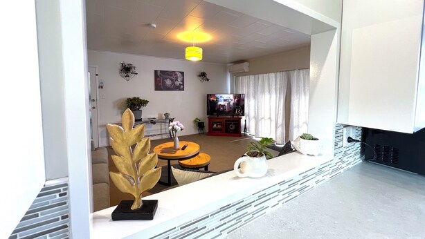 A modern living room with a sofa, coffee table, and decorative plants. There is a television and a fireplace. - Rotorua Central Accommodation  (Rotorua)