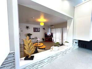 Un salon moderne avec un canapé, une table basse et des plantes décoratives. On y trouve également une télévision et une cheminée.