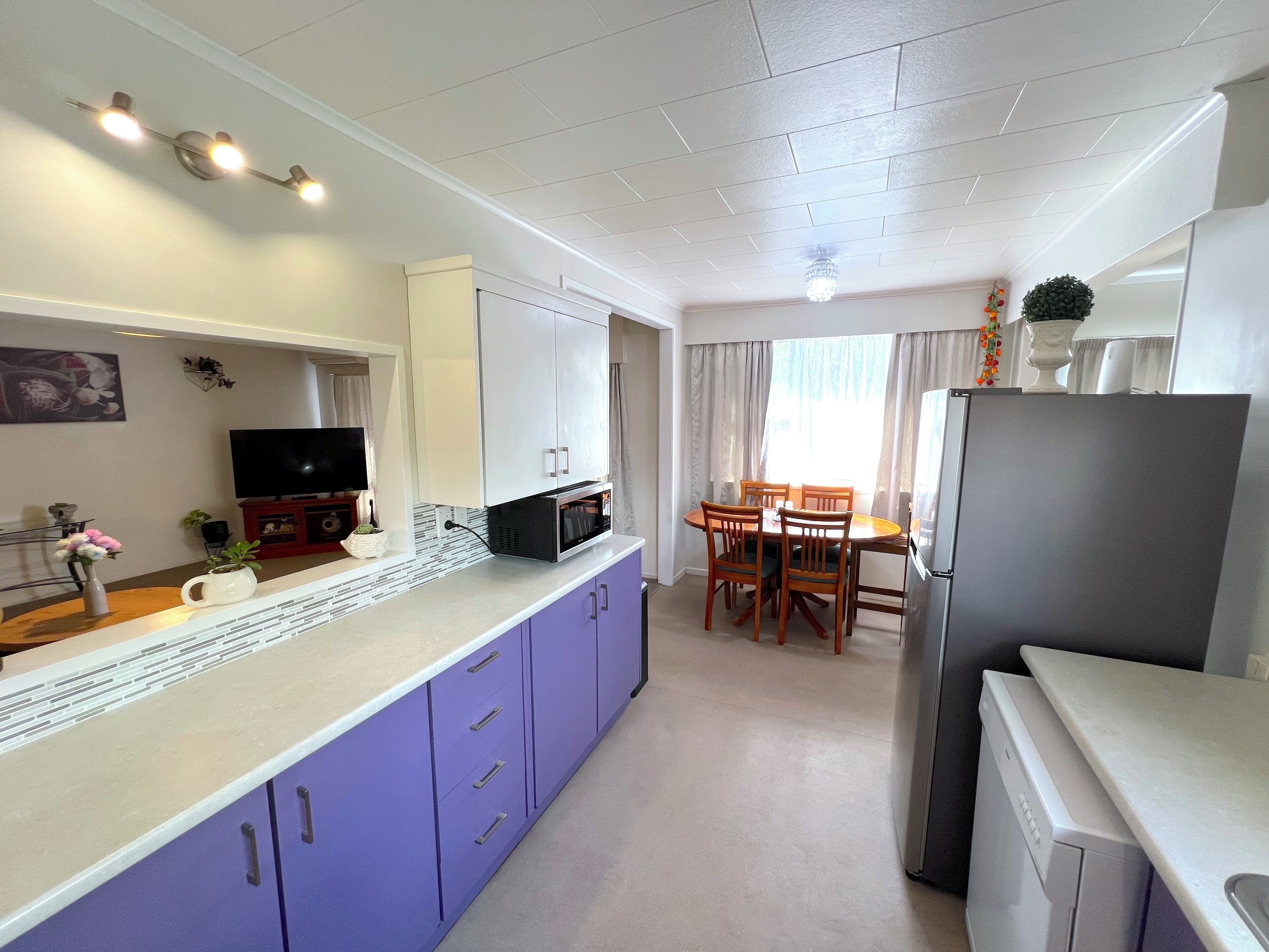 A compact kitchen with a microwave, refrigerator, and dining area with chairs and a table.