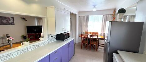 A compact kitchen with a microwave, refrigerator, and dining area with chairs and a table.
