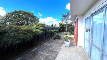 Un sendero estrecho que lleva a un edificio con puerta de garaje, rodeado de plantas y árboles.