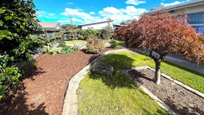 A well-maintained garden with a variety of plants and a small tree with red leaves. - Rotorua Central Accommodation  (Rotorua)