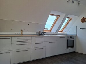 A modern kitchen with skylights, a built-in oven, and a stainless steel sink.