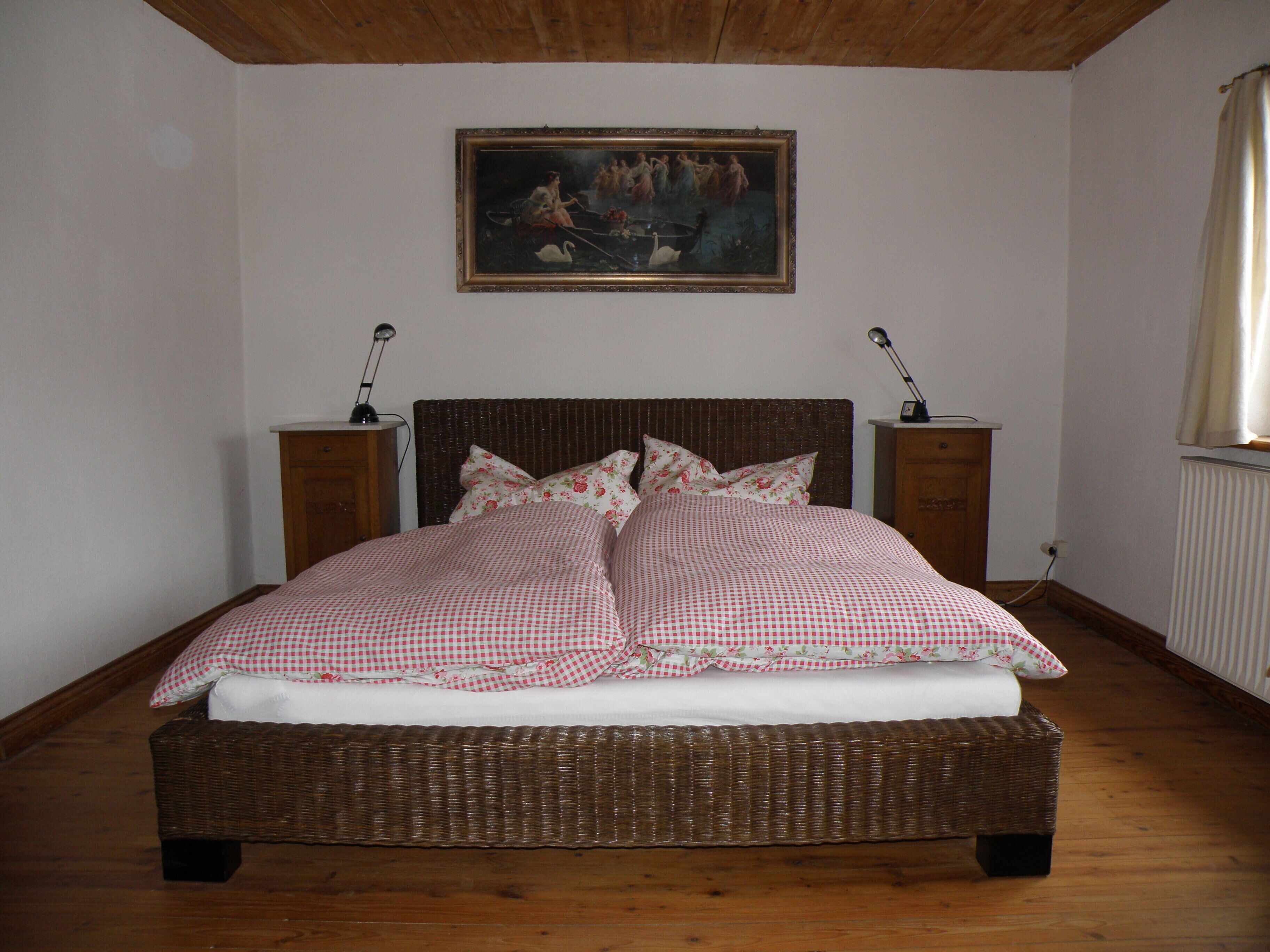 Ein Schlafzimmer mit einem großen Bett, einem Gemälde an der Wand und zwei Nachttischlampen.