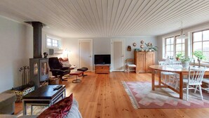 A spacious living room with a fireplace, a television, and a dining area with a table and chairs.